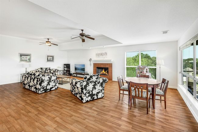 Living room featuring light wood finished floors, ceiling fan, and a tile fireplace | Image 14