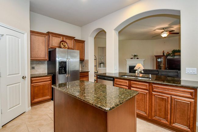 Modern kitchen with rich wood cabinetry, granite countertops, and stainless steel appliances. | Image 12