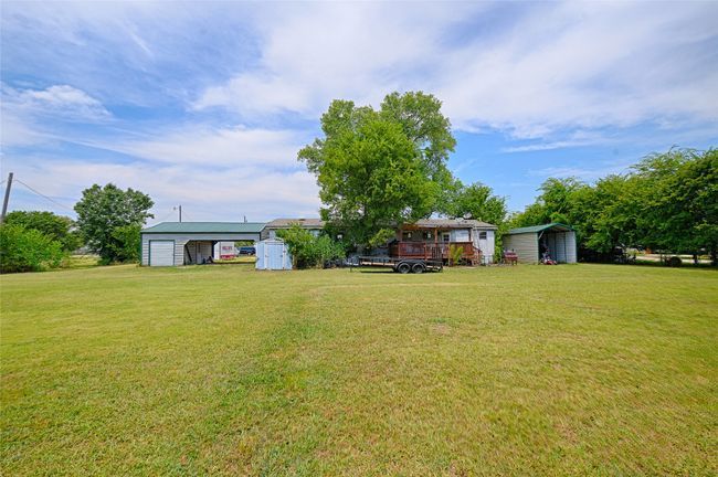 View of grassy yard with a storage unit and a carport | Image 25