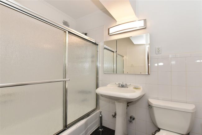 Full bathroom with combined bath / shower with glass door, toilet, tile walls, and ornamental molding | Image 20