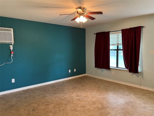 Spare room with a ceiling fan, a wall mounted air conditioner, and baseboards | Image 18