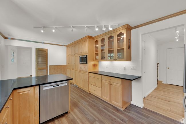 Kitchen with stainless steel appliances, dark countertops, rail lighting, and crown molding | Image 9