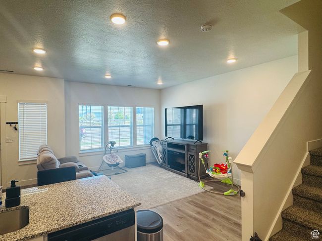 Living area featuring wood finished floors, a textured ceiling, recessed lighting, and stairway | Image 5