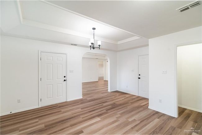 Spare room with light wood-type flooring, arched walkways, visible vents, and a tray ceiling | Image 6