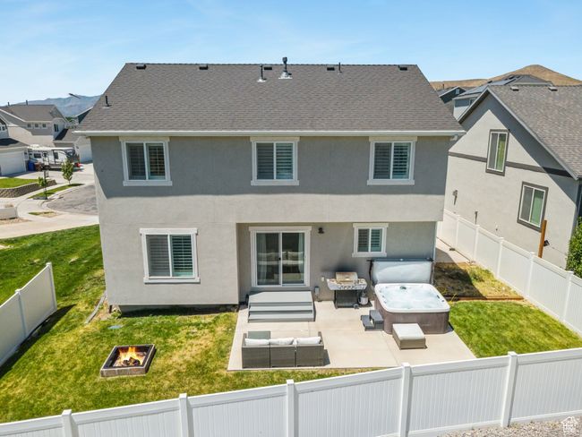 Back of house with a hot tub, an outdoor living space with a fire pit, a fenced backyard, and a patio area | Image 38