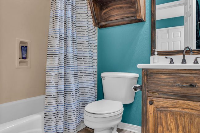 Bathroom featuring vanity, toilet, a textured wall, and shower / bath combo | Image 16