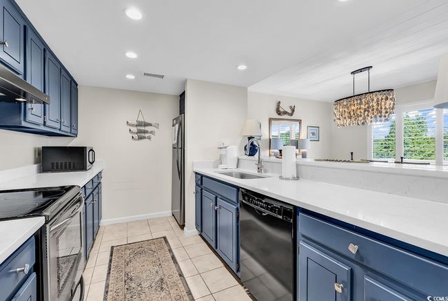 Kitchen featuring light countertops, a sink, black appliances, and blue cabinetry | Image 6