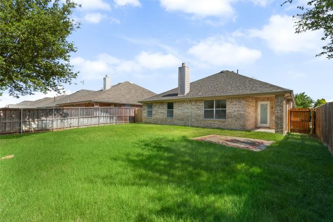 Back of house featuring a chimney, roof with shingles, a fenced backyard, brick siding, and a patio area | Image 24