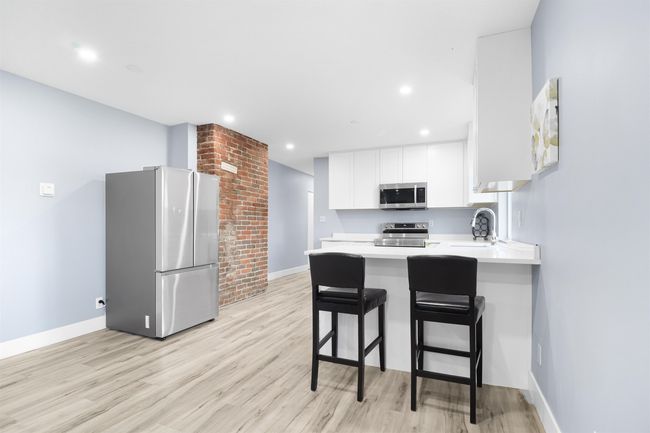 Kitchen featuring white cabinetry, light countertops, baseboards, light wood finished floors, and appliances with stainless steel finishes | Image 7
