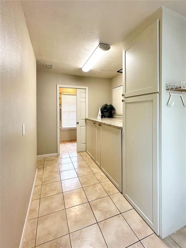 A generously extended laundry room ensures convenience for managing daily household needs. Full restroom is closed off by the pocket door | Image 13
