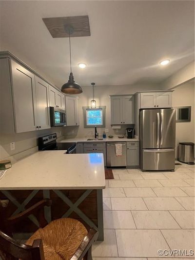 Kitchen with sink, gray cabinetry, light tile patterned floors, stainless steel appliances, and pendant lighting | Image 3