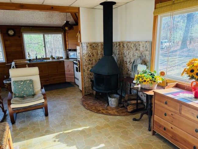 Kitchen featuring a wood stove, wood walls, sink, and white appliances | Image 7