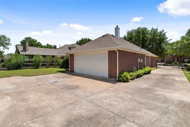 Ranch-style home featuring a chimney, brick siding, a gate, concrete driveway, and roof with shingles | Image 40