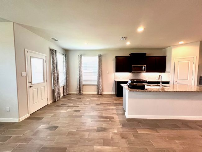 Kitchen featuring stainless steel microwave, light stone counters, recessed lighting, light wood-type flooring, and backsplash | Image 5