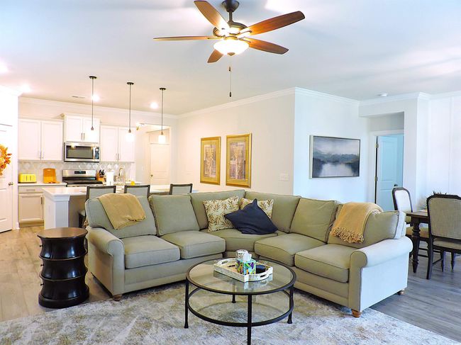 Living area featuring light wood-type flooring, a ceiling fan, and crown molding | Image 11