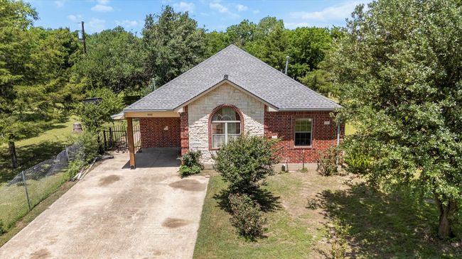 View of front facade with driveway, stone siding, roof with shingles, and fence | Image 25