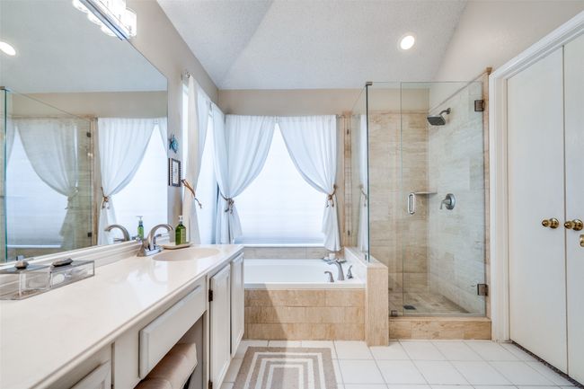 Updated in 2020, the primary bath boasts a lovely travertine tile surround for the jetted tub and separate shower area with frameless glass. | Image 18