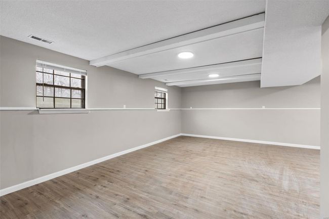 Basement with baseboards, visible vents, wood finished floors, and a healthy amount of sunlight | Image 22