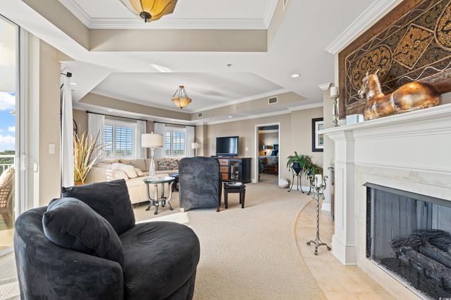 Living room featuring a tray ceiling, crown molding, light carpet, a fireplace with flush hearth, and recessed lighting | Image 7