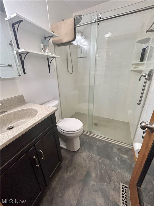 Bathroom featuring toilet, a shower with shower door, and vanity with extensive cabinet space | Image 13