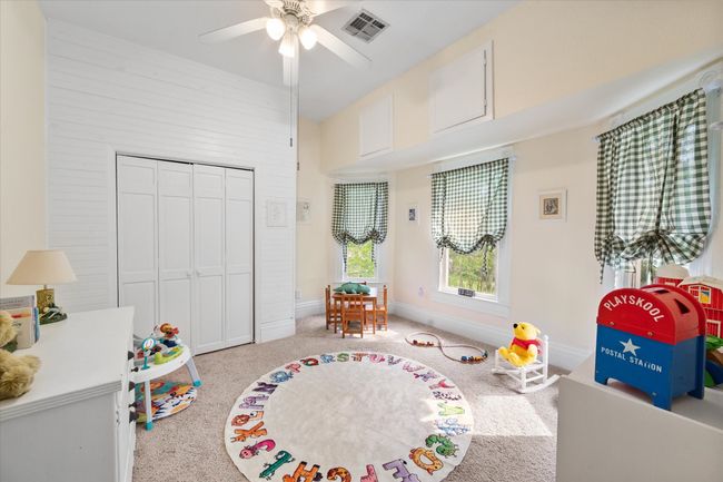 Recreation room with a ceiling fan, carpet flooring, and baseboards. Playroom. | Image 25