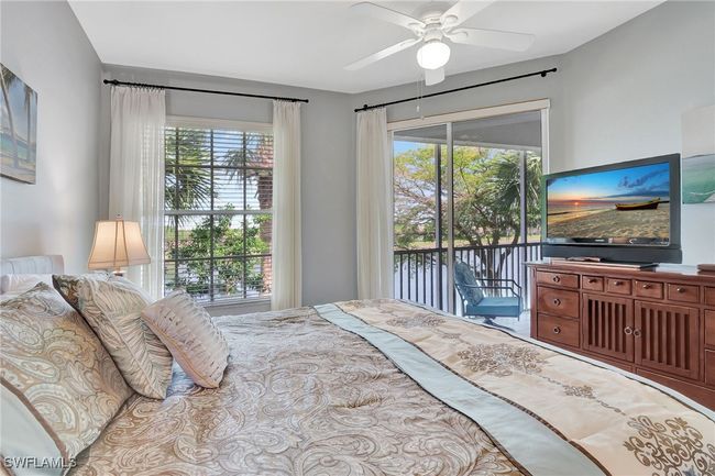 Spacious Primary Bedroom overlooking the lake, featuring access to exterior lanai multiple windows, and ceiling fan | Image 22