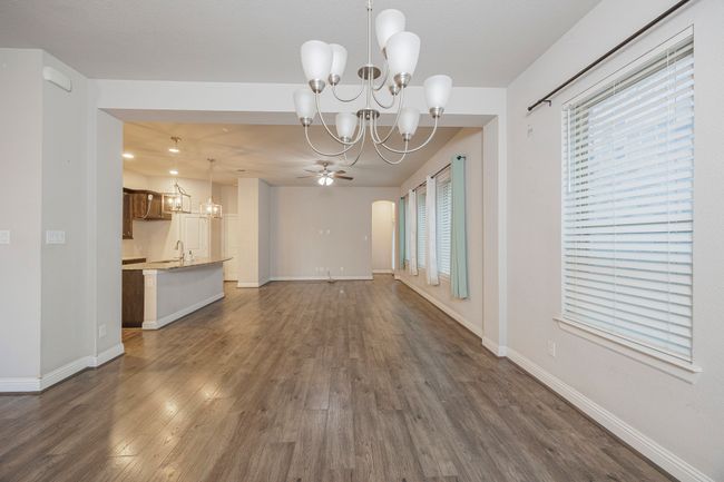Unfurnished living room featuring a chandelier, a ceiling fan, and dark wood-style floors | Image 13