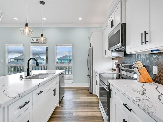 The oversized island with a deep single basin stainless steel sink and a sleek black pull-down faucet makes prepping, serving, and entertaining as easy breezy as an evening on the balcony! | Image 16