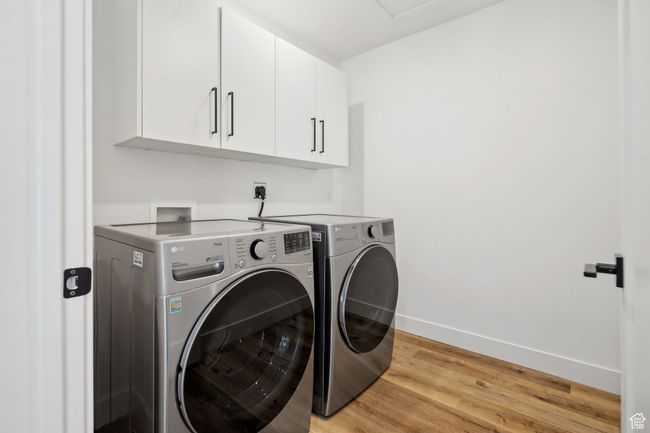 Laundry area with cabinet space, light wood finished floors, baseboards, and washer and clothes dryer | Image 22