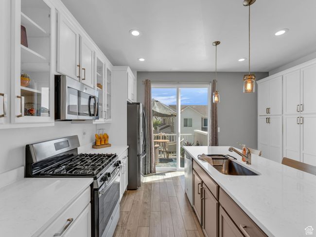 Kitchen with stainless steel appliances, recessed lighting, light wood finished floors, glass insert cabinets, and white cabinetry | Image 12