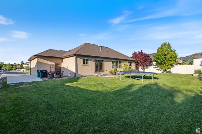 Back of house featuring entry steps, a trampoline, and a shingled roof | Image 19