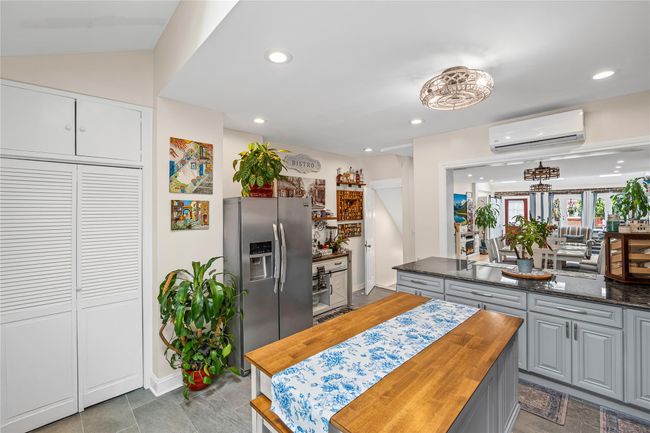 Kitchen featuring stainless steel fridge with ice dispenser, an AC wall unit, wooden counters, gray cabinets, and recessed lighting | Image 13