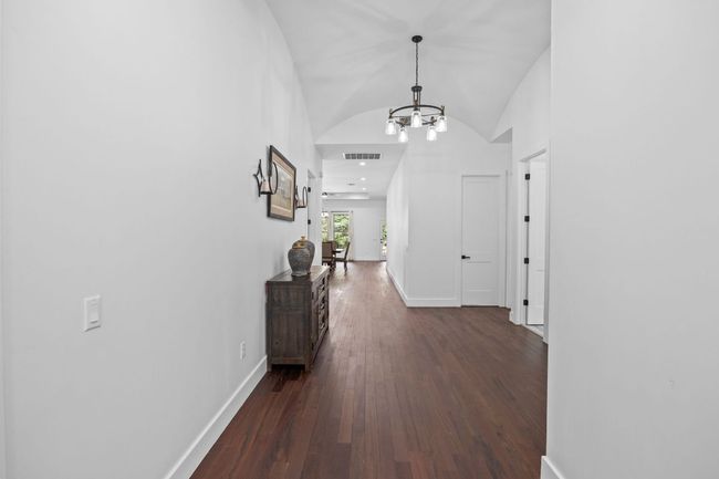 Hallway featuring a chandelier, dark wood-style flooring, and vaulted ceiling | Image 5