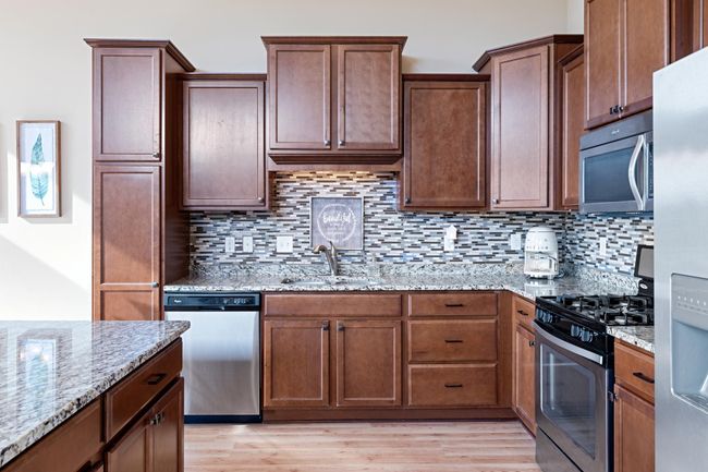 Spacious kitchen with large island, tons of cabinets and storage, stainless steel appliances, tile backsplash and granite counters. | Image 6
