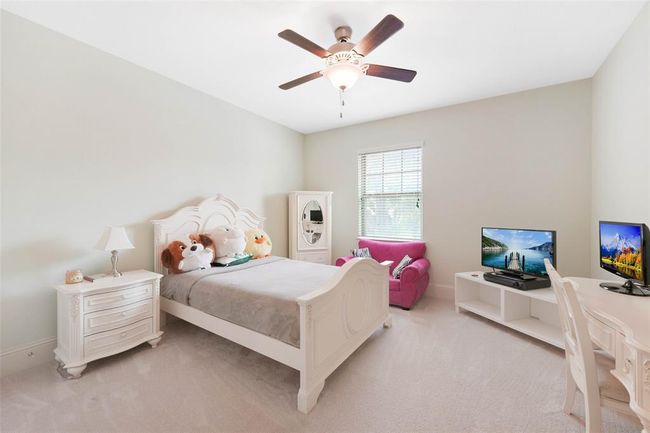 Charming secondary bedroom with plush carpet, ceiling fan, and soft natural light. Spacious enough for a bed, study space, and seating area—perfect for children, guests, or flexible use. | Image 32