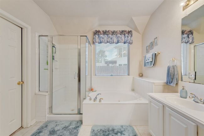 Full bathroom with tile patterned floors, a shower stall, a garden tub, vanity, and vaulted ceiling | Image 25
