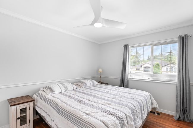 Bedroom featuring dark wood-type flooring, crown molding, baseboards, and a ceiling fan | Image 18