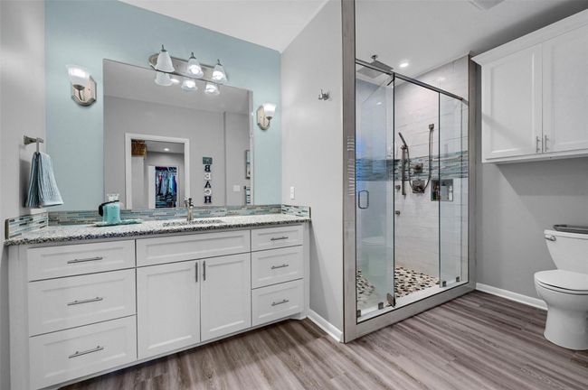 Bathroom with toilet, wood finished floors, vanity, a stall shower, and baseboards | Image 26