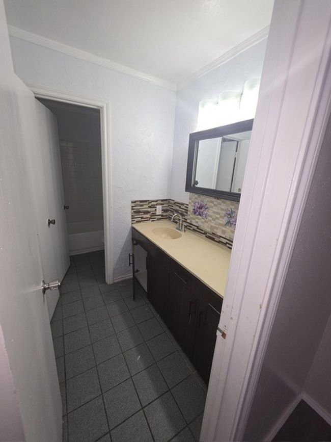 Bathroom with vanity, tile patterned floors, ornamental molding, and backsplash | Image 5