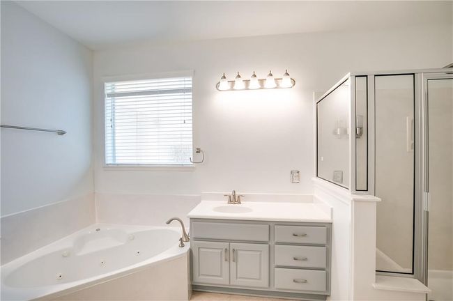 Bathroom with a stall shower, vanity, and a whirlpool tub | Image 19