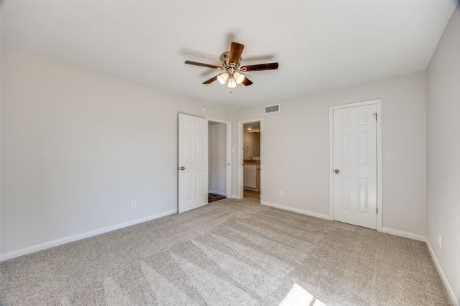 Unfurnished bedroom featuring a closet, ceiling fan, ensuite bathroom, and light carpet | Image 16