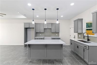 Kitchen with backsplash, gray cabinetry, sink, and a kitchen island | Image 2