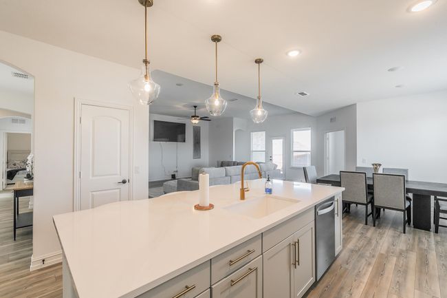 Kitchen featuring dishwasher, a kitchen island with sink, hanging light fixtures, sink, and ceiling fan | Image 9