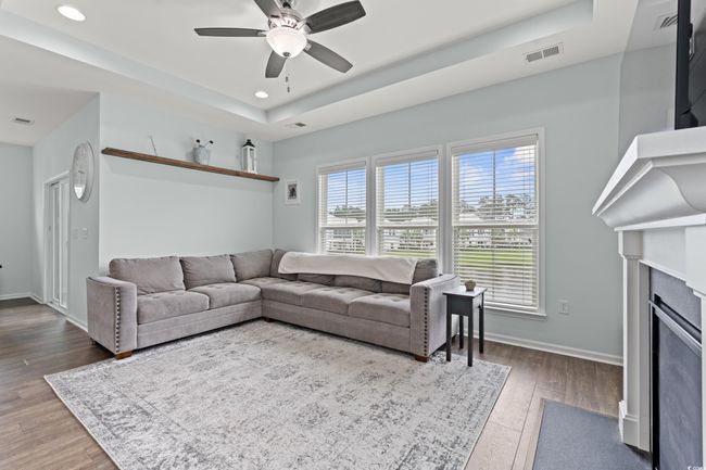 Open Concept living area on the second level featuring recessed lighting, a tray ceiling, ceiling fan, large gas fireplace and large windows with a pond view. | Image 23
