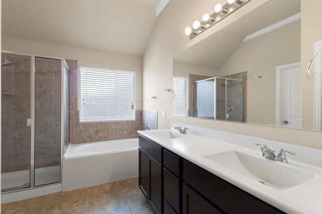 Full bath featuring lofted ceiling, a shower stall, plenty of natural light, a garden tub, and double vanity | Image 17