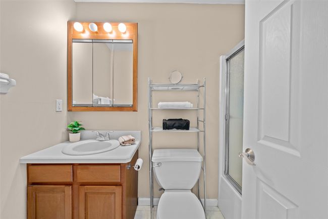 Bathroom featuring vanity, toilet, baseboards, tile patterned floors, and enclosed tub / shower combo | Image 25