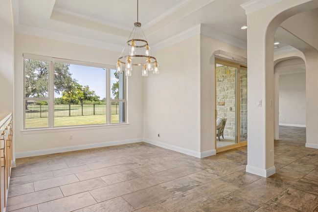 Dining area with arched walkways, crown molding, a chandelier and convenient access to the back patio | Image 22