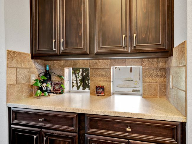 Kitchen countertops, cabinetry, and decorative backsplash with windows and natural light | Image 19