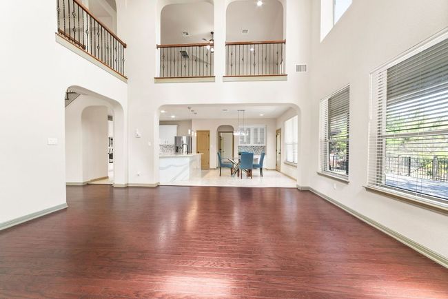 Unfurnished living room with wood finished floors, a towering ceiling, arched walkways, and a ceiling fan | Image 12