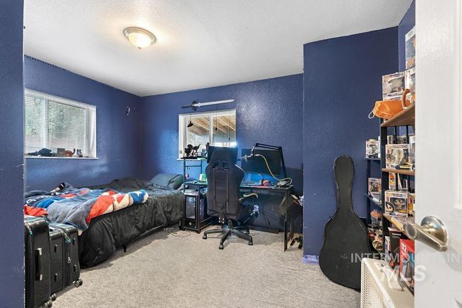 Carpeted bedroom featuring multiple windows, a textured wall, a textured ceiling, and an office area | Image 30